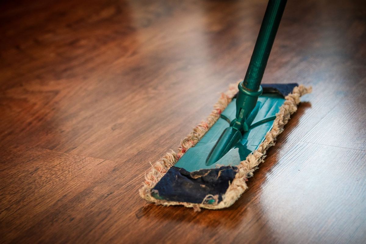 A dust mop being pushed across a hardwood floor
