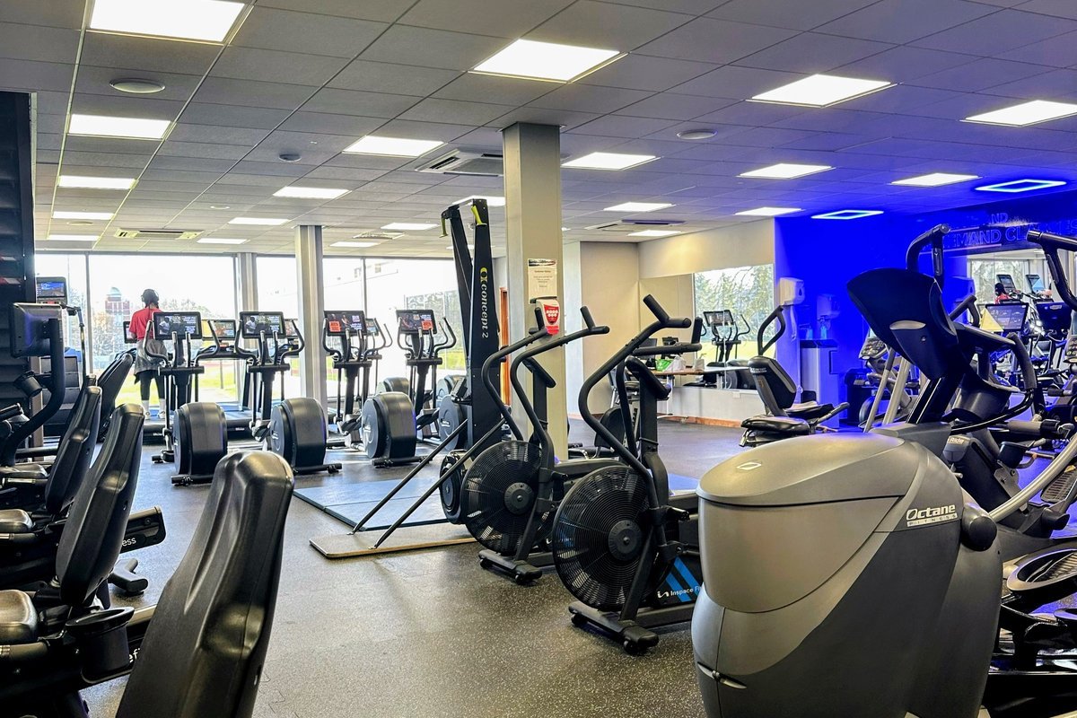 A floor scrubber machine parked among cardio machines in a gym