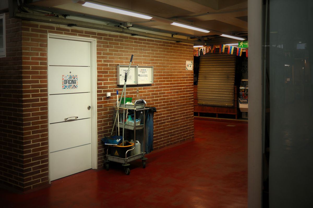 A stocked janitorial cart parked in a brick office hallway