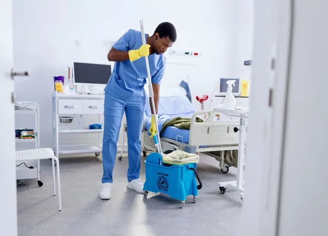 Janitor in scrubs mopping the floor of a medical room: janitorial services in Manassas, VA