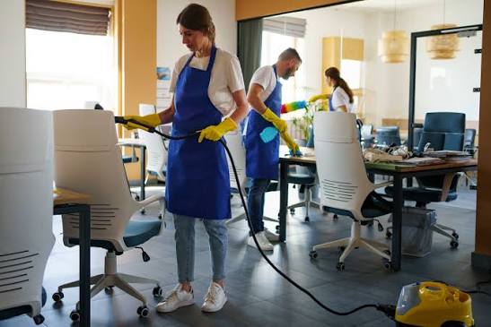Cleaners vacuuming and wiping desks in an office: office cleaning services in Arlington, VA